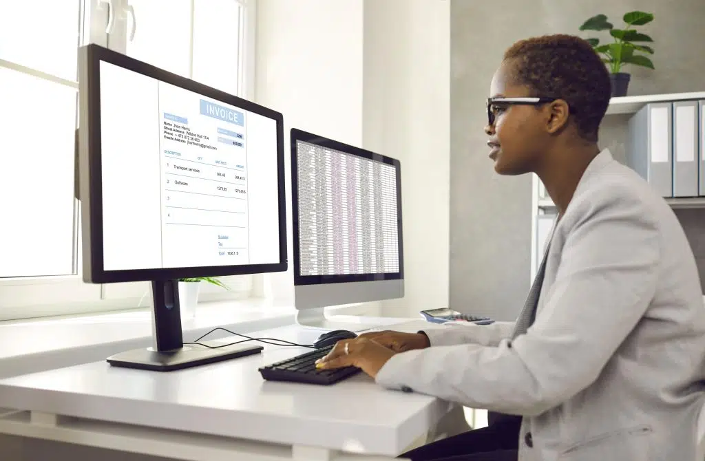 a young woman reviews invoice on computer using e-invoicing software 